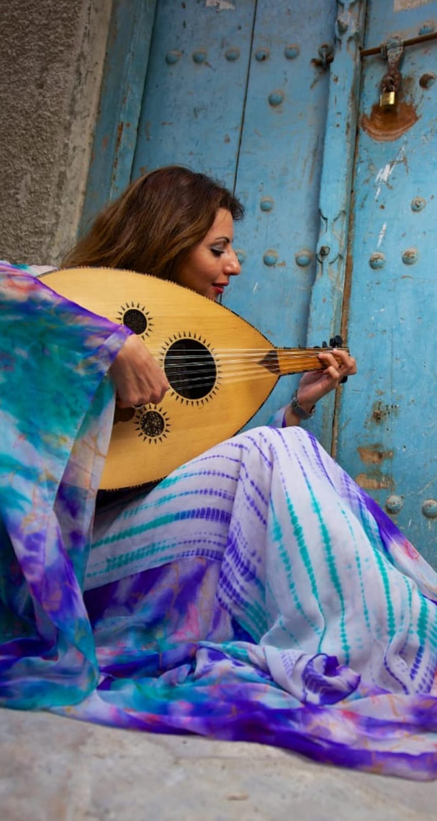 Nina Oud, Arabic singer and oud player, performing beside a weathered blue door